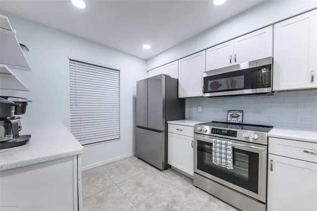 a kitchen with stainless steel appliances granite countertop white cabinets a microwave a sink and a refrigerator