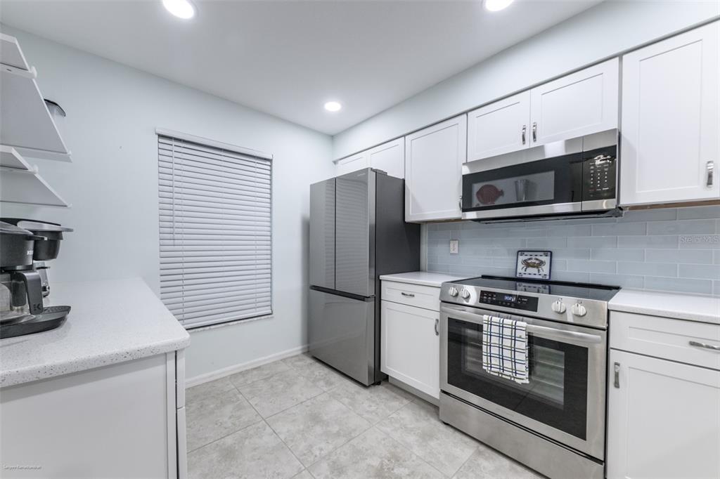 220 Coldeway Drive, Unit 112 Punta Gorda, FL 33950 - Photo 4 of 49 a kitchen with stainless steel appliances granite countertop white cabinets a microwave a sink and a refrigerator