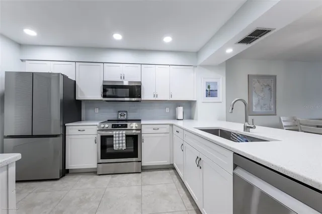 a kitchen with stainless steel appliances granite countertop a sink a stove a refrigerator and a microwave