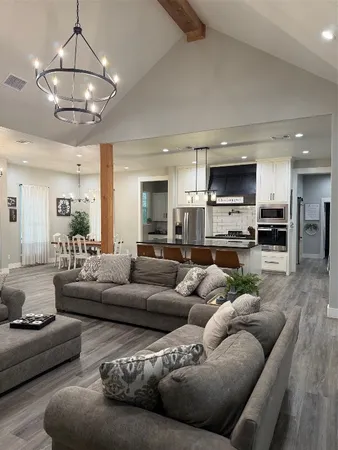 a living room with furniture kitchen view and a chandelier