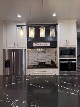 a kitchen with stainless steel appliances granite countertop a stove a sink and a microwave