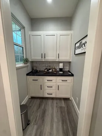 a view of kitchen with granite countertop white cabinets and window