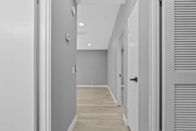 a view of a hallway with wooden floor and a bathroom