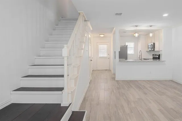 a view of a hallway with wooden floor and a cabinet