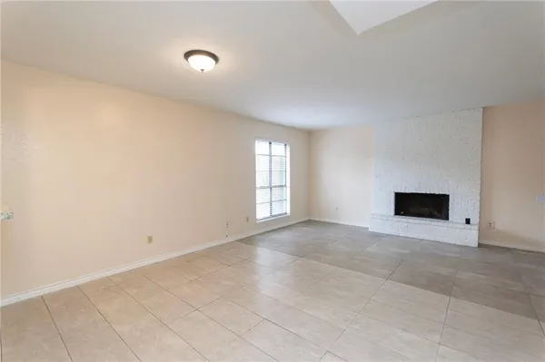 an empty room with windows and fireplace
