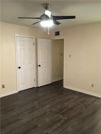 a view of an empty room with wooden floor and a ceiling fan