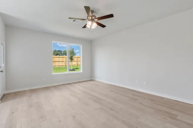 an empty room with a window and a ceiling fan
