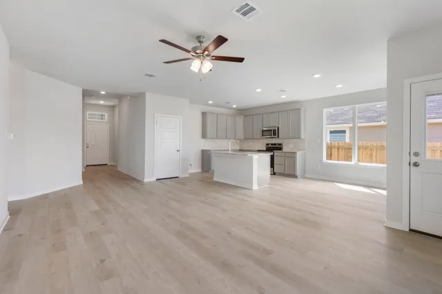 a view of a electric appliances in kitchen and empty room with wooden floor