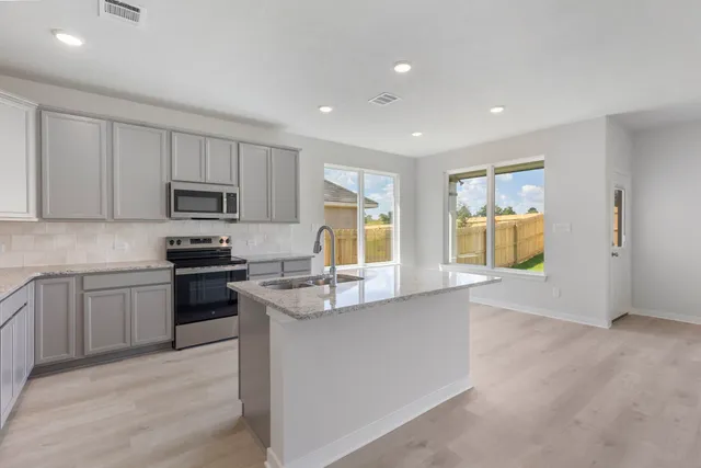 a kitchen with stainless steel appliances granite countertop a stove a sink a refrigerator and a microwave