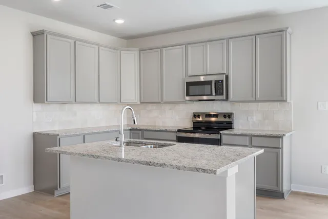 a kitchen with granite countertop a sink stove and microwave