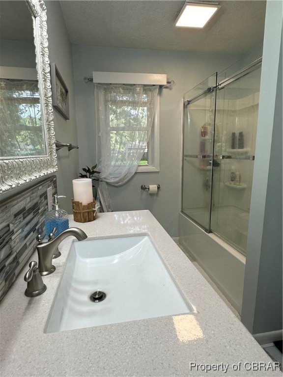 7809 Ark Road Gloucester, VA 23061 - Photo 14 of 32 Bathroom featuring vanity, a textured ceiling, backsplash, and enclosed tub / shower combo