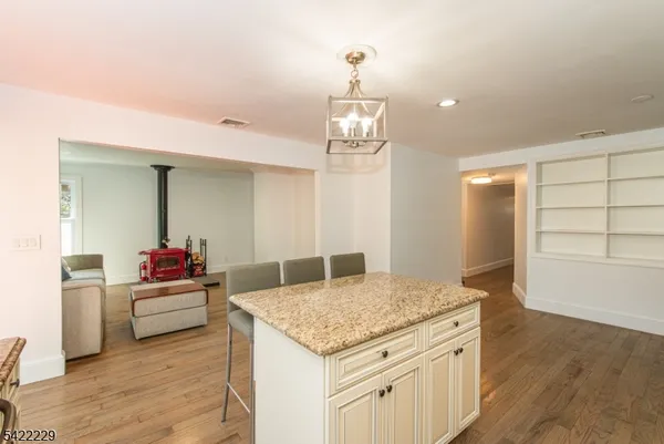 a living room with kitchen island granite countertop wooden floor and chandelier