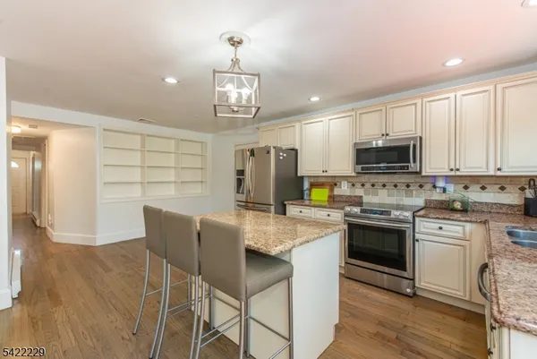a kitchen with stainless steel appliances granite countertop a stove top oven a sink dishwasher a dining table and chairs with wooden floor