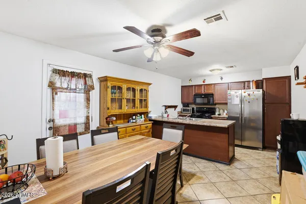 a dining room with stainless steel appliances kitchen island granite countertop a dining table and chairs with wooden floor