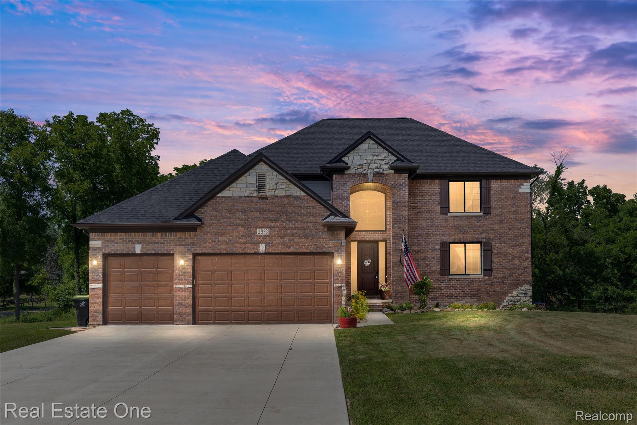 2983 28 Mile Road Washington, MI 48094 - Photo 1 of 54 Brick exterior featuring a two-car garage, arched entry, dark wood shutters, and stone accents