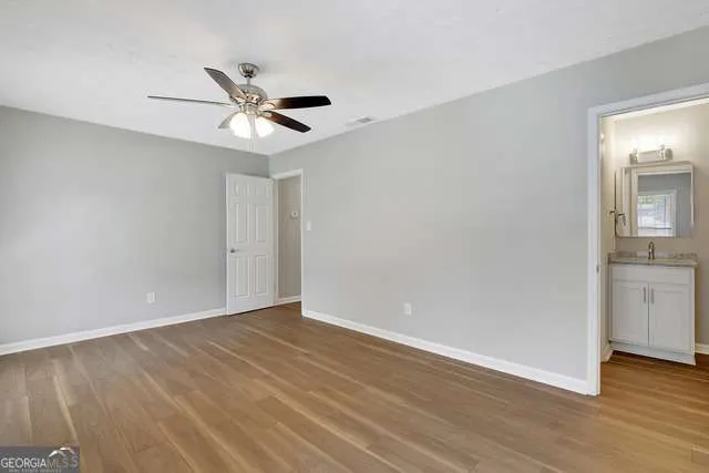 an empty room with wooden floor a ceiling fan and entryway