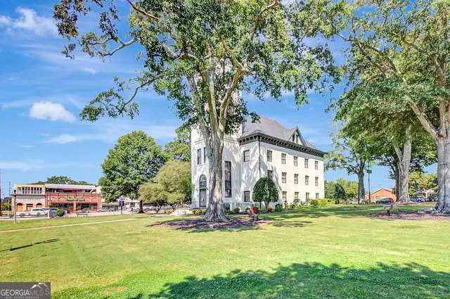a front view of a building with a garden and trees