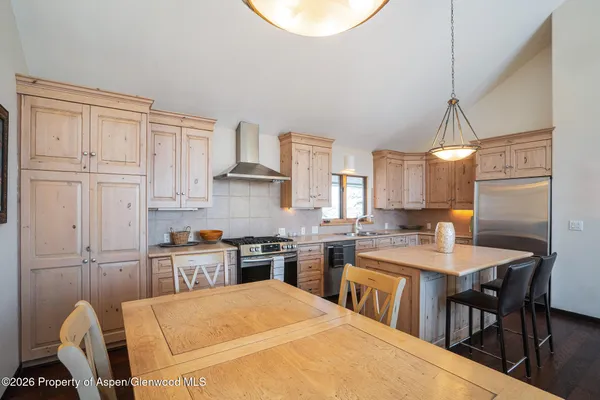 a kitchen with stainless steel appliances granite countertop a stove a sink a dining table and chairs with wooden floor