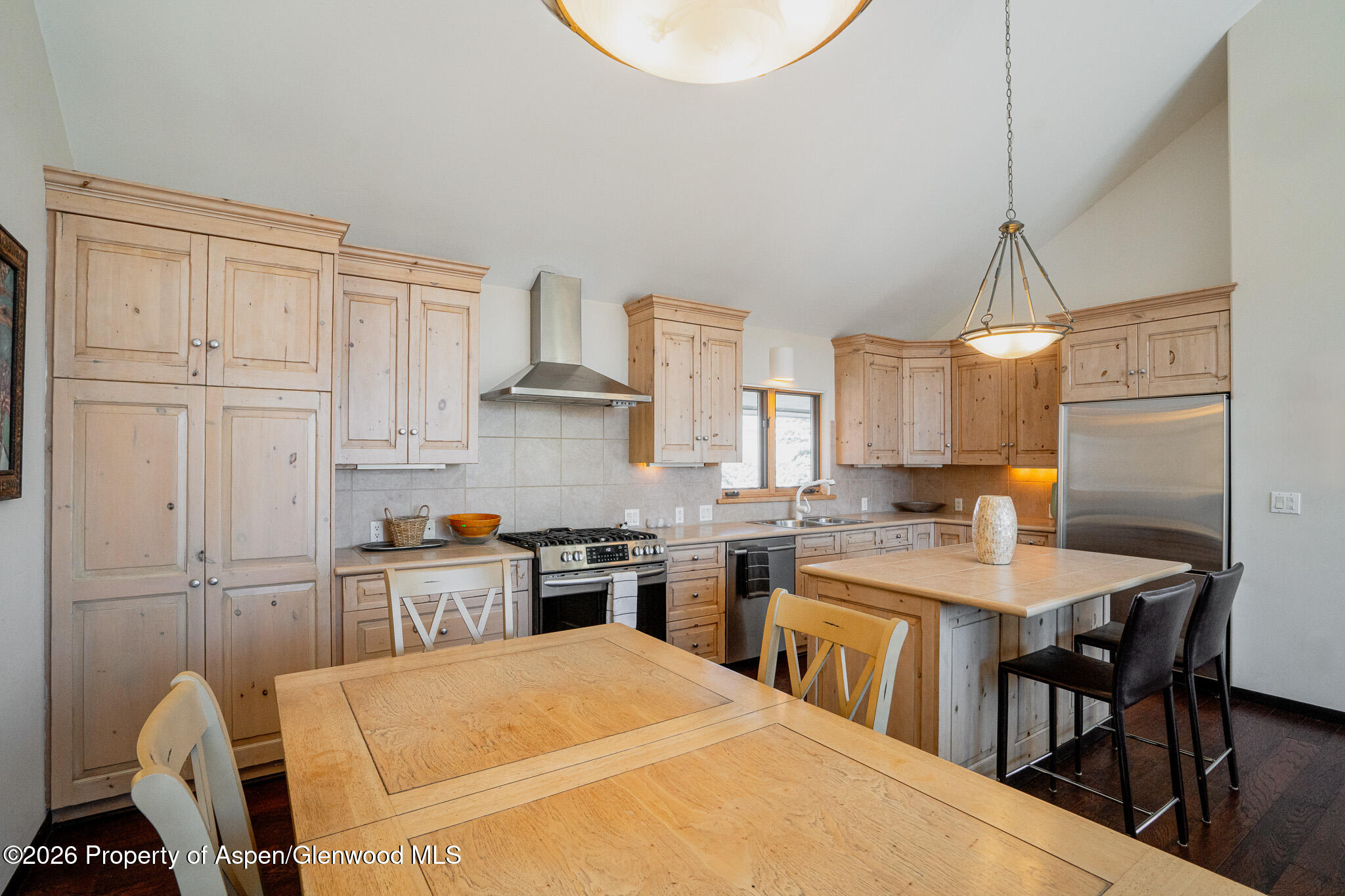 2310 Juniper Hill Road Aspen, CO 81611 - Photo 36 of 50 a kitchen with stainless steel appliances granite countertop a stove a sink a dining table and chairs with wooden floor