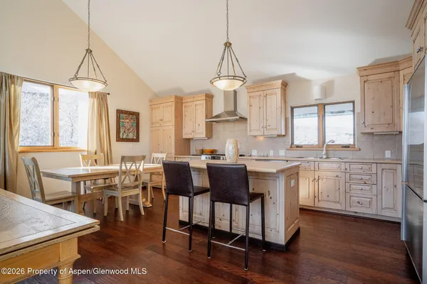 a open kitchen with stainless steel appliances granite countertop a kitchen island hardwood floor sink stove dining table and chairs