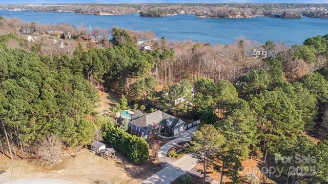 an aerial view of a houses with outdoor space and trees all around