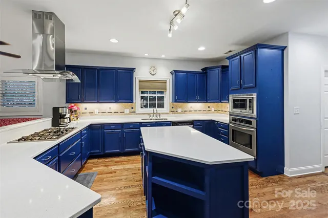 a kitchen with stainless steel appliances kitchen island granite countertop a sink stove and refrigerator