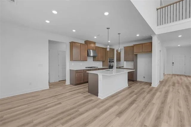 a large kitchen with a large counter top a sink stainless steel appliances and cabinets