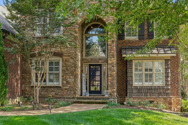 a front view of a house with a garden and trees