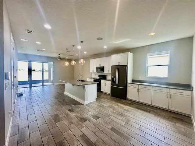 a large kitchen with stainless steel appliances kitchen island granite countertop a large counter top and a stove top oven