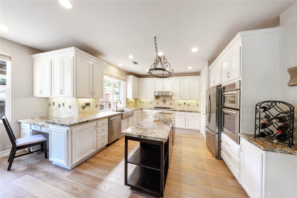 6402 Camino Ventosa San Clemente, CA 92673 - Photo 10 of 67 a large kitchen with stainless steel appliances kitchen island granite countertop a large stove a sink dishwasher and white cabinets with wooden floor