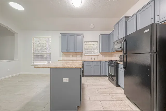 a kitchen with a refrigerator sink and cabinets