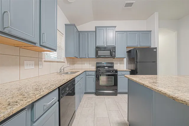 a kitchen with kitchen island granite countertop a sink stove and refrigerator