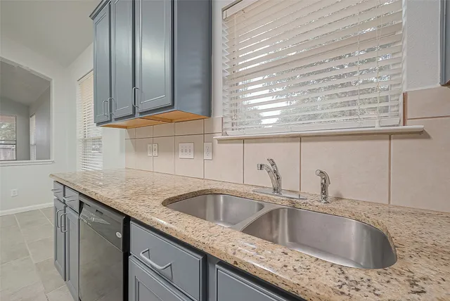 a kitchen with a granite countertop sink and natural light