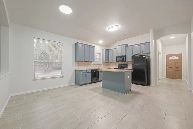 a kitchen with stainless steel appliances granite countertop a refrigerator a sink a stove a microwave and white cabinets