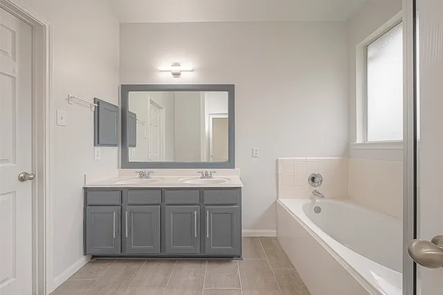 a bathroom with a bath tub a sink and mirror