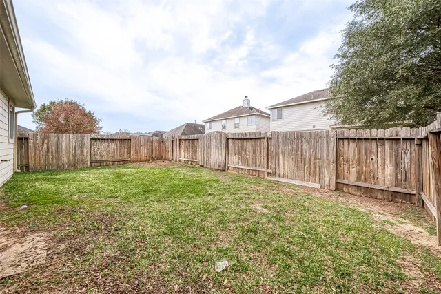 a backyard of a house with plants and large tree