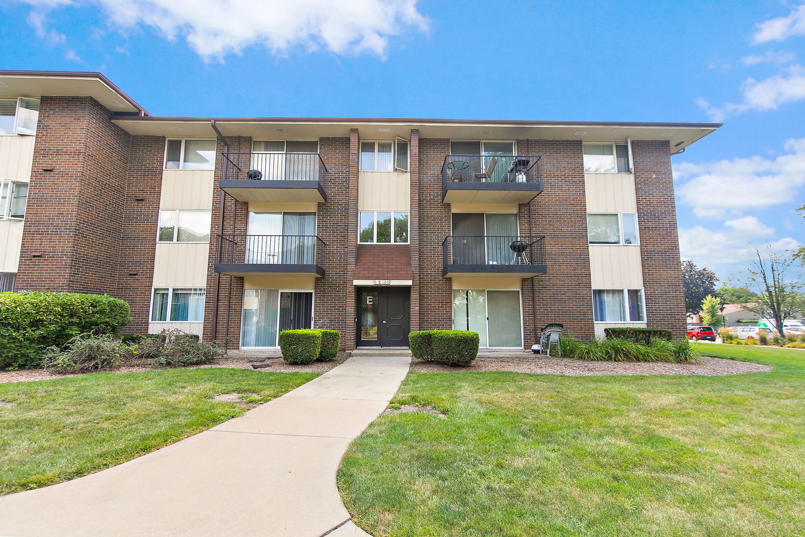 5s100 Pebblewood Lane, Unit E6 Naperville, IL 60563 - Photo 1 of 18 a front view of a building with a garden