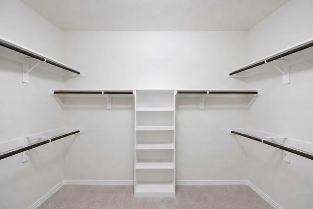 an empty room with chandelier fan and windows