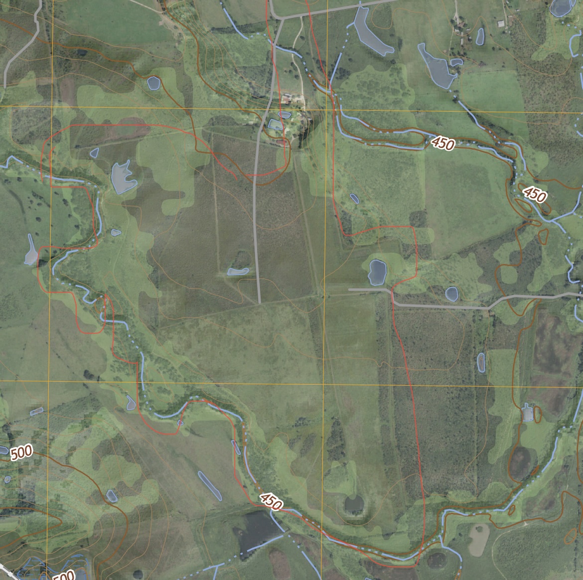 An aerial view revealing the property's boundaries, winding waterways, and serene ponds across varied terrain.