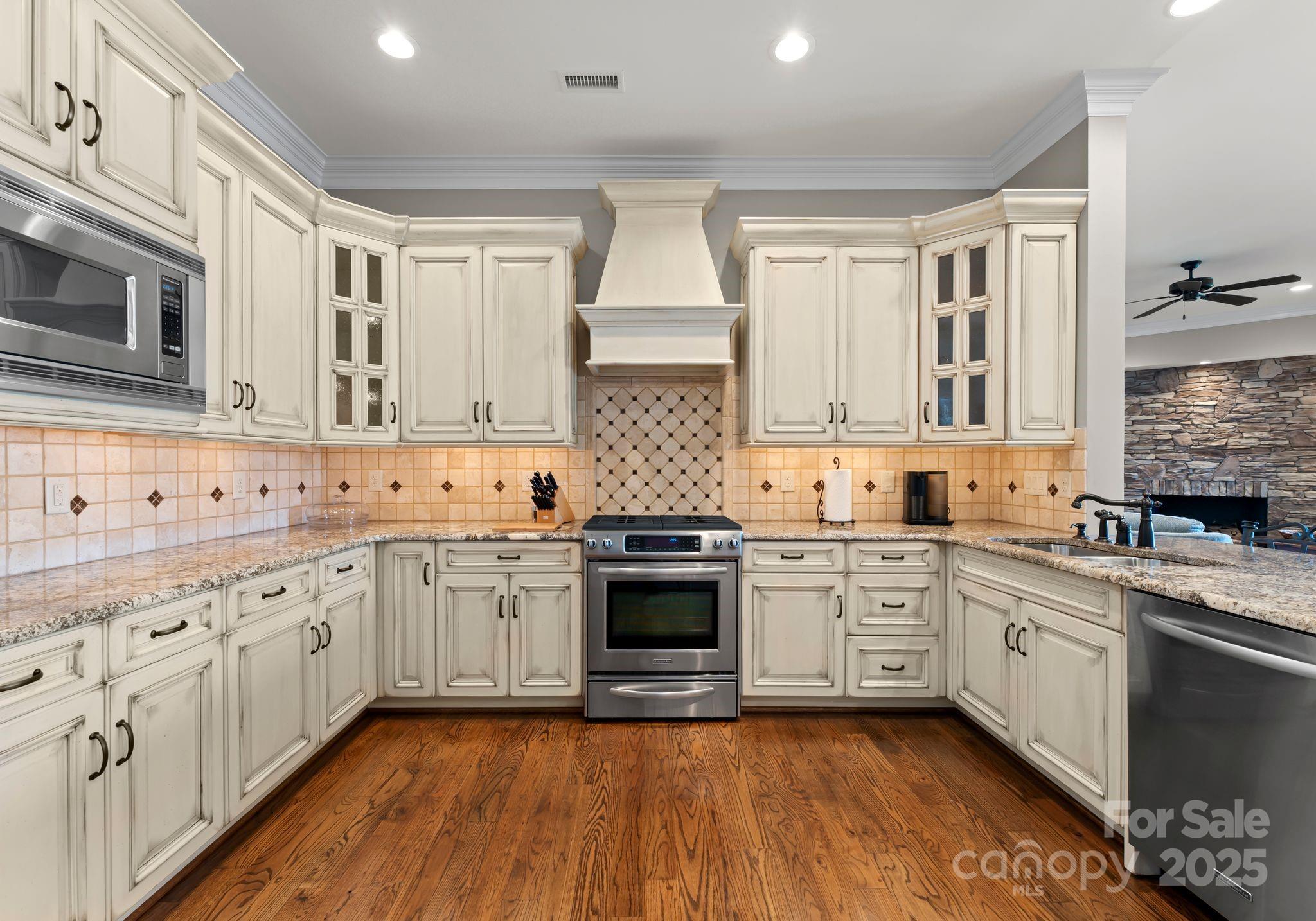 4004 Channel Point Lane Denver, NC 28037 - Photo 28 of 48 a kitchen with granite countertop white cabinets stainless steel appliances a sink and wooden floor