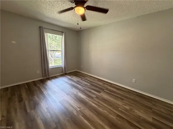 an empty room with a window and a ceiling fan