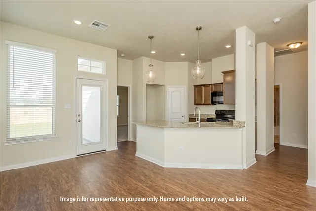 a view of a kitchen with kitchen island a refrigerator wooden floor and a view of living room