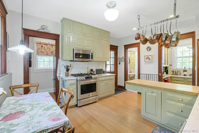 a large kitchen with a stove a sink dishwasher a dining table and chairs with wooden floor