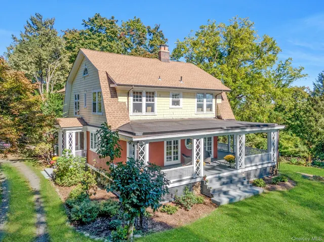 an aerial view of a house with yard and trees in the background