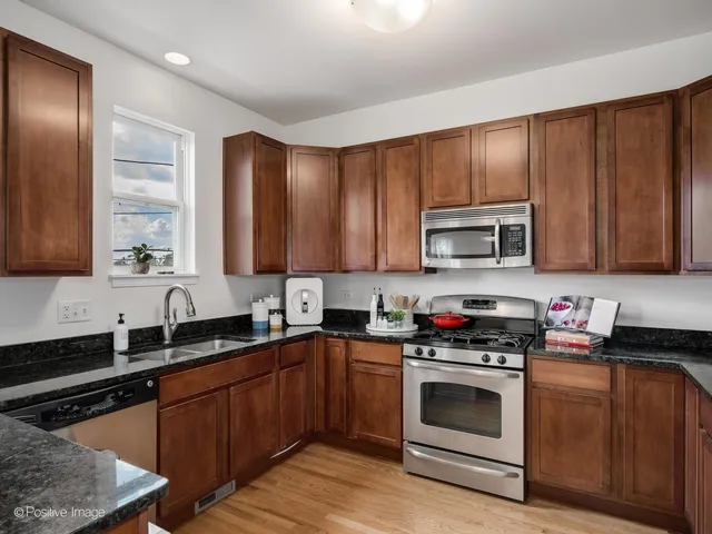 a kitchen with granite countertop wooden cabinets stainless steel appliances and a sink