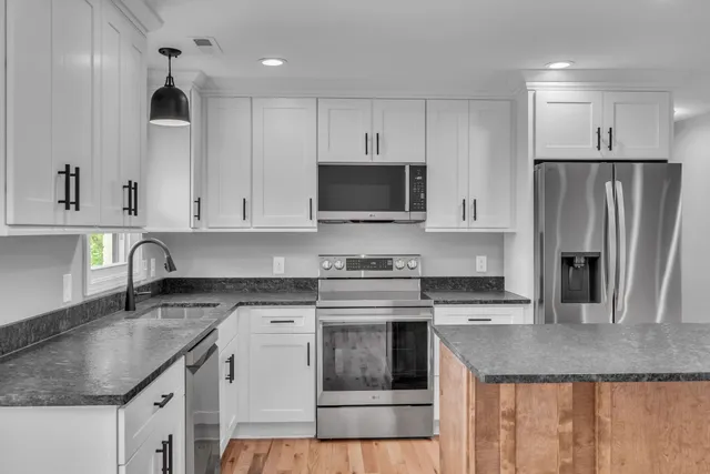 a kitchen with granite countertop a sink a stove and refrigerator