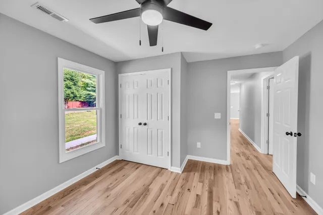 a view of an empty room with window and wooden floor