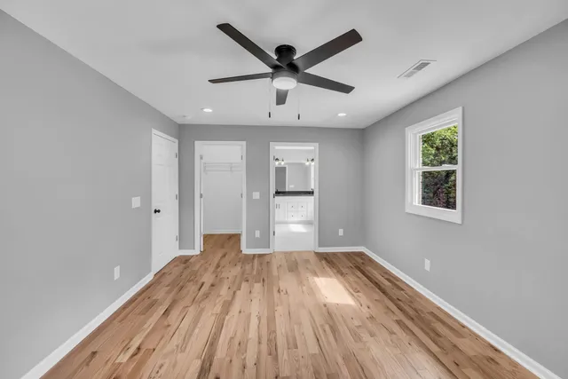 a view of empty room with wooden floor and ceiling fan