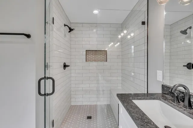 a bathroom with a sink shower and a mirror