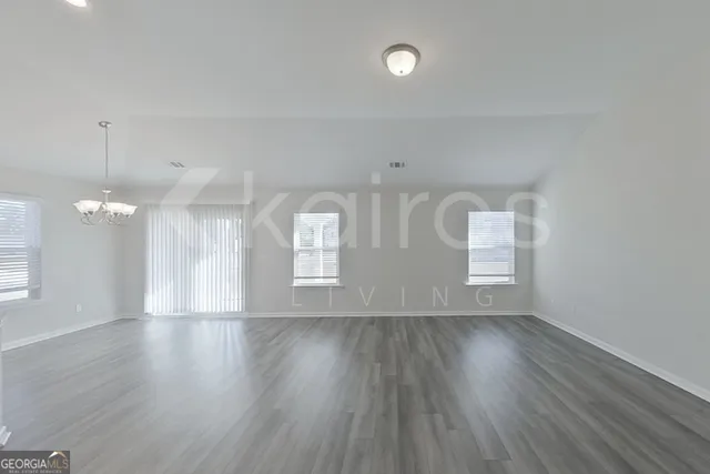 a view of an empty room with wooden floor and window